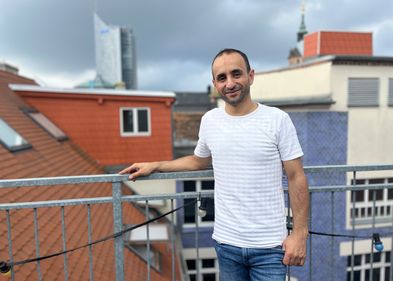 Absolvent Samer Arbash, Foto: Lina Hörügel Auf dem Bild ist Alumnus Samer Arbash vor der Silhouette Leipzigs zu sehen.