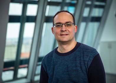 Foto: Humboldt-Stiftung Daniel Král steht in einem Gebäude der Universität Leipzig vor einem Fenster.