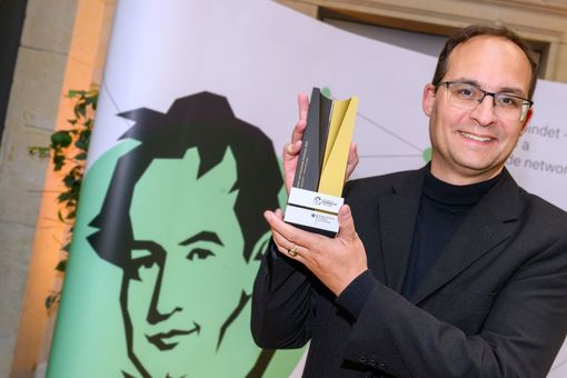Professor Daniel Kráľ holding a Humboldt Foundation trophy.