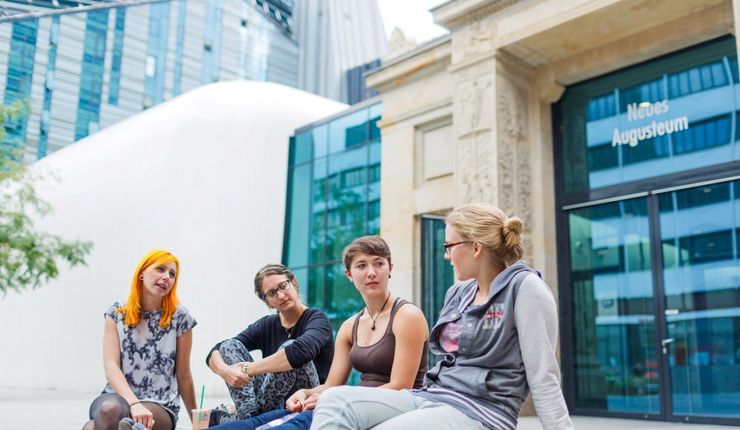 Vier Studierende sitzen im Innenhof zusammen und reden miteinander, Foto: Christian Hüller