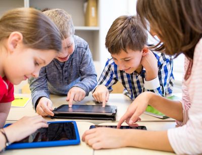 group of school kids with tablet pc computer having fun in classroom