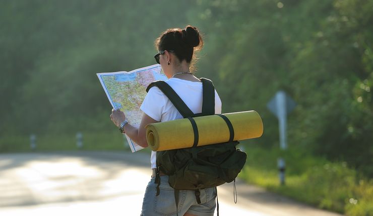 Junge Frau mit Rucksack schaut sich Landkarte an