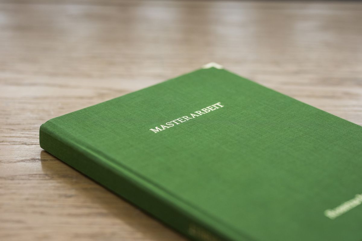 Grünes Buch mit dem Titel Masterarbeit liegt geschlossen auf dem Tisch, Foto: Christian Hüller